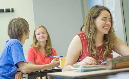 Estudiantes jóvenes sonriendo tomando clases de inglés en el extranjero