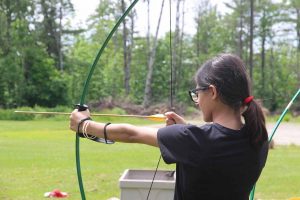 Adolescente aprendiendo a tirar con el arco en Campamento de Swallowdale con StudyWorld